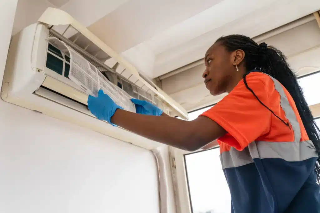 HVAC Technician is diligently cleaning an air conditioner for optimal performance.